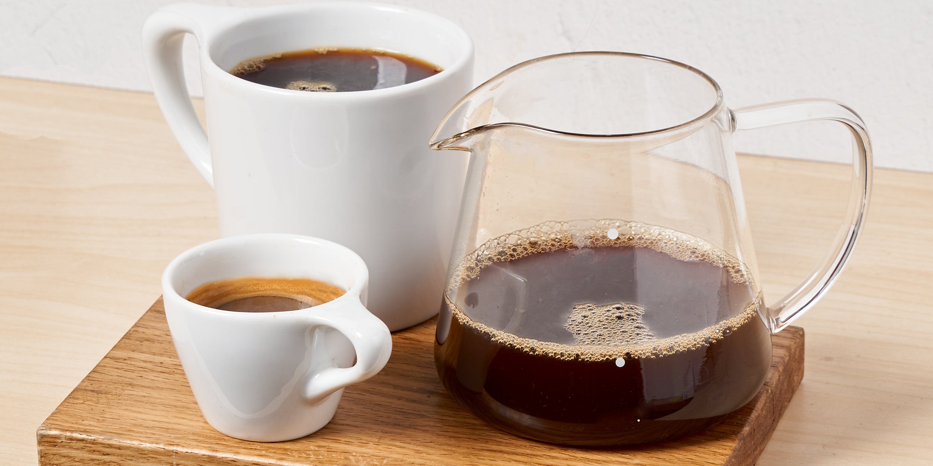 photograph of glass vessel, ceramic mug, and espresso cup filled with coffee