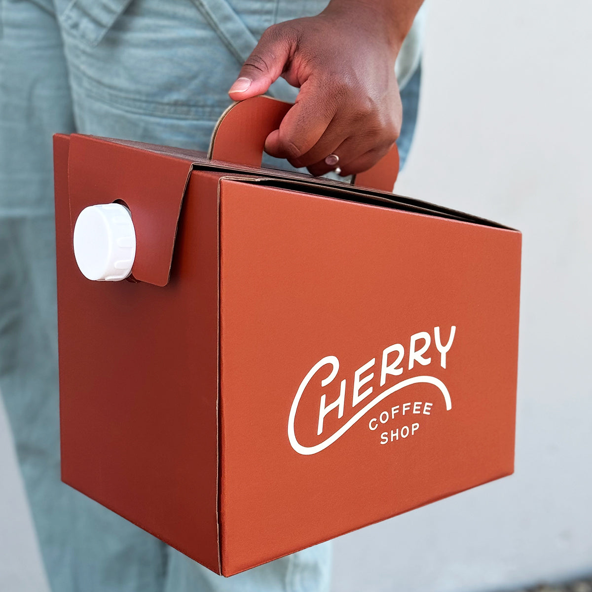 woman holding a cherry coffee shop drip carrier