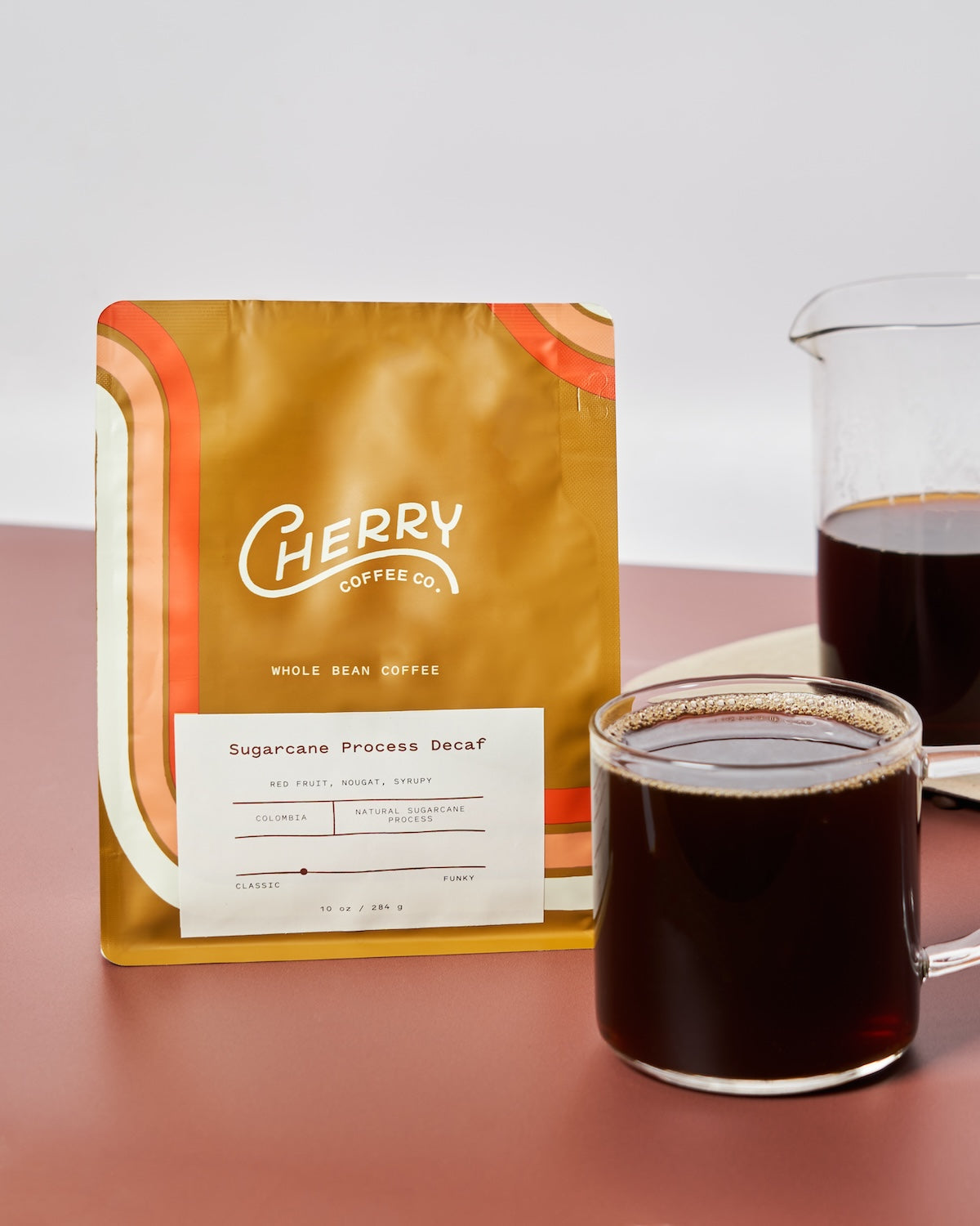 photograph of 'sugarcane process decaf' coffee next to a cup and carafe of brewed coffee