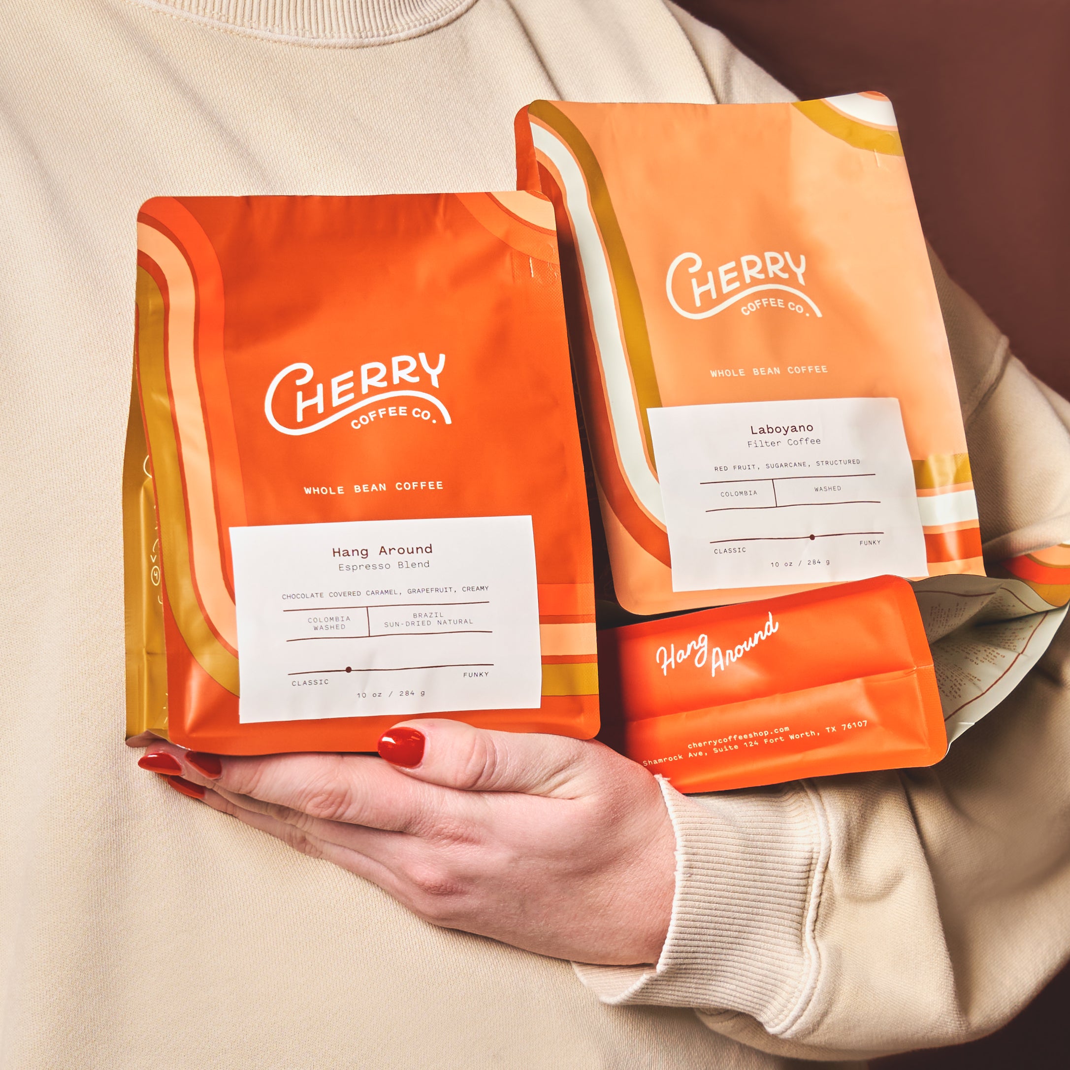 photograph of an arm holding 3 bags of whole bean cherry coffee