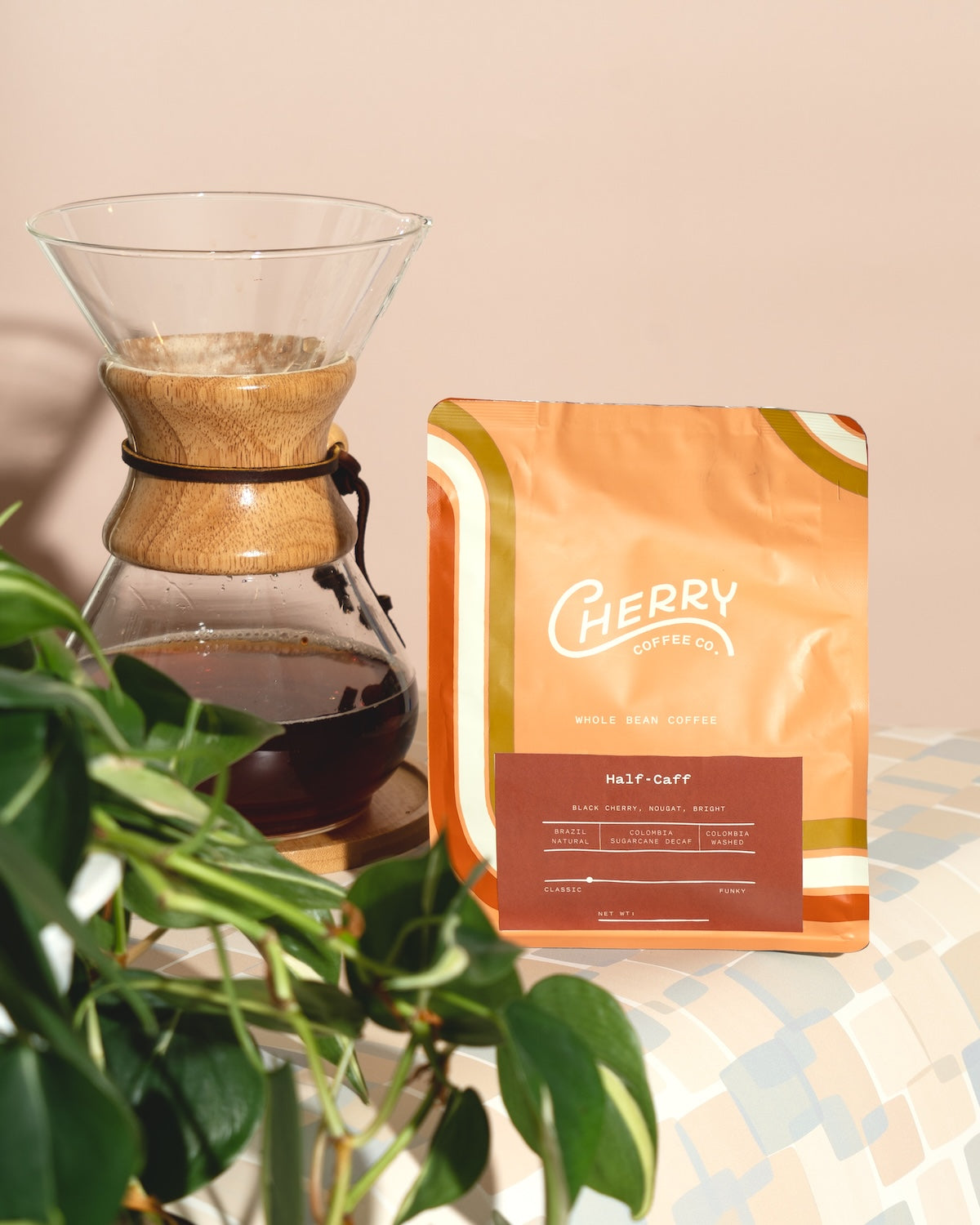 photograph of Cherry Coffee's Half-Caff blend, next to a Chemex filled with coffee and a plant
