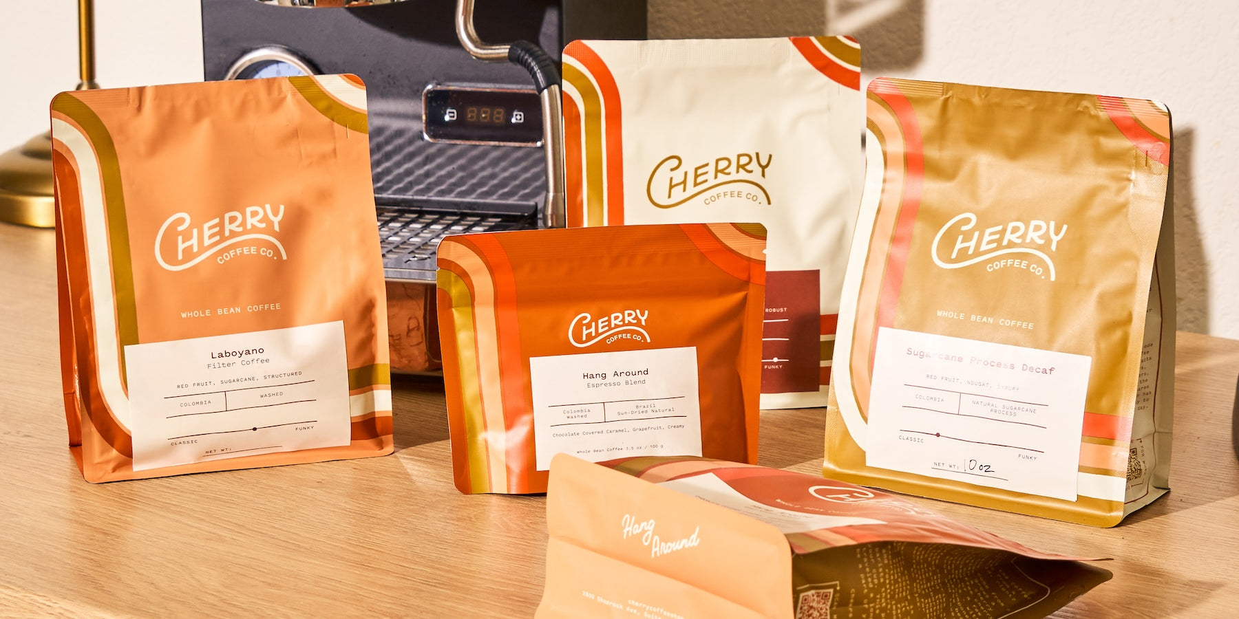 Photography of an assortment of 5 cherry coffee bags  on a coffee bar with an expresso machine