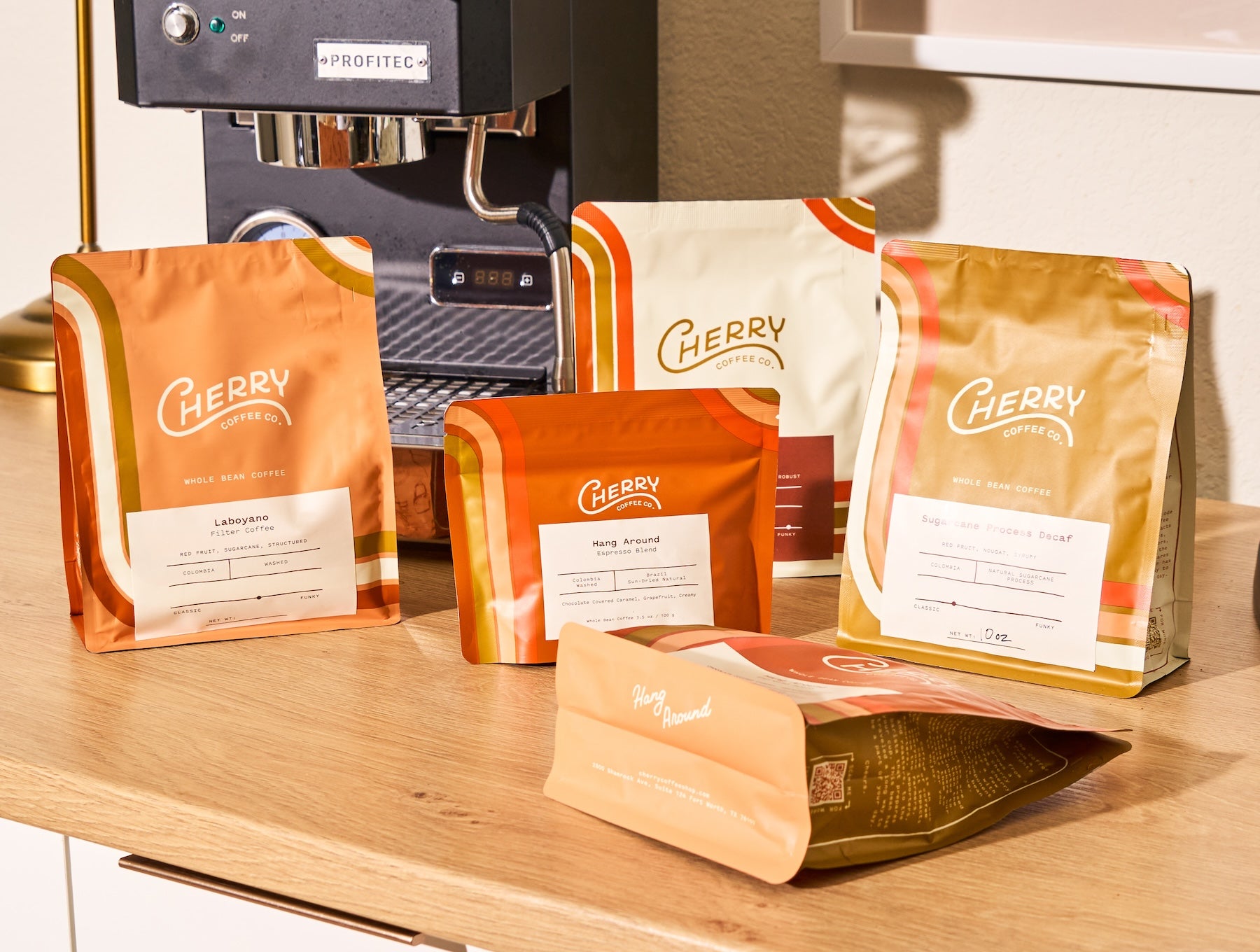 Photography of an assortment of 5 cherry coffee bags  on a coffee bar with an expresso machine