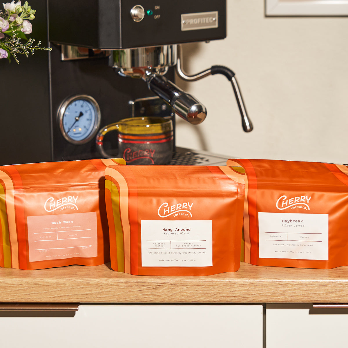 photograph of three Cherry Coffee sample sized coffee bags in front of espresso machine